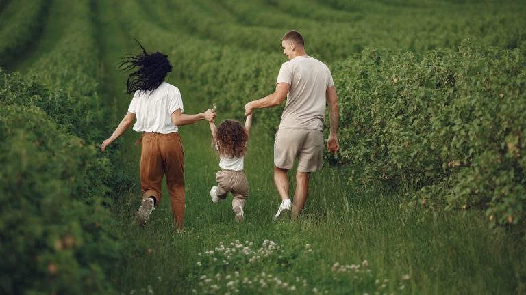 A joyful family strolls through a lush green field, enjoying quality time together.