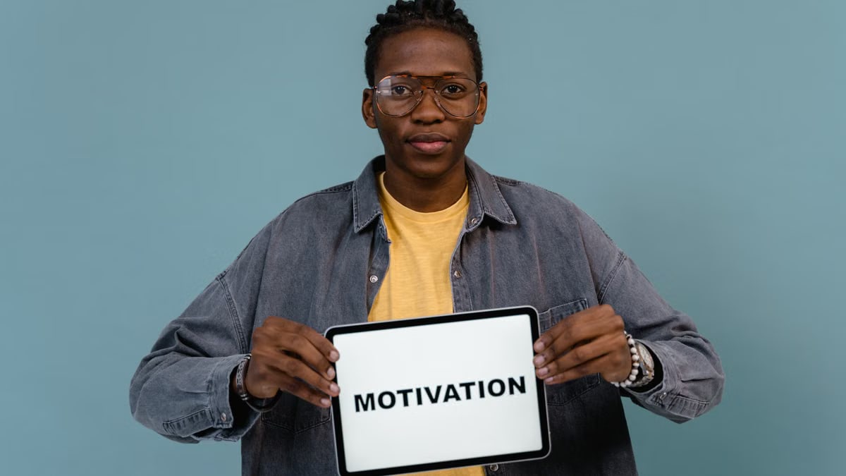 A young African American man holding a tablet displaying the word 'MOTIVATION' against a blue background.